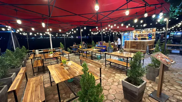 Habibi Eatery open-air terrace at night with wooden tables, red canopies, string lights and the Habibi bar